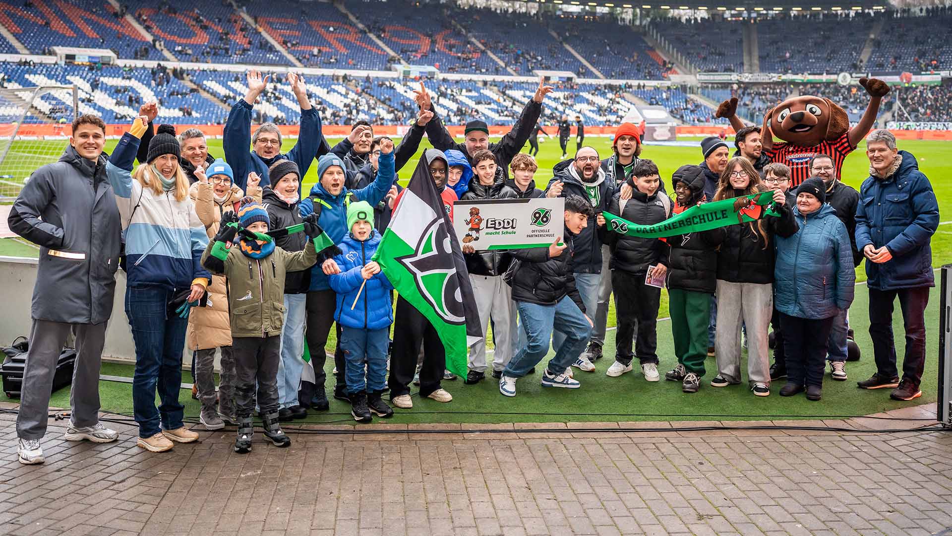 Eine Partnerschule posiert mit der Plakette im Stadion.