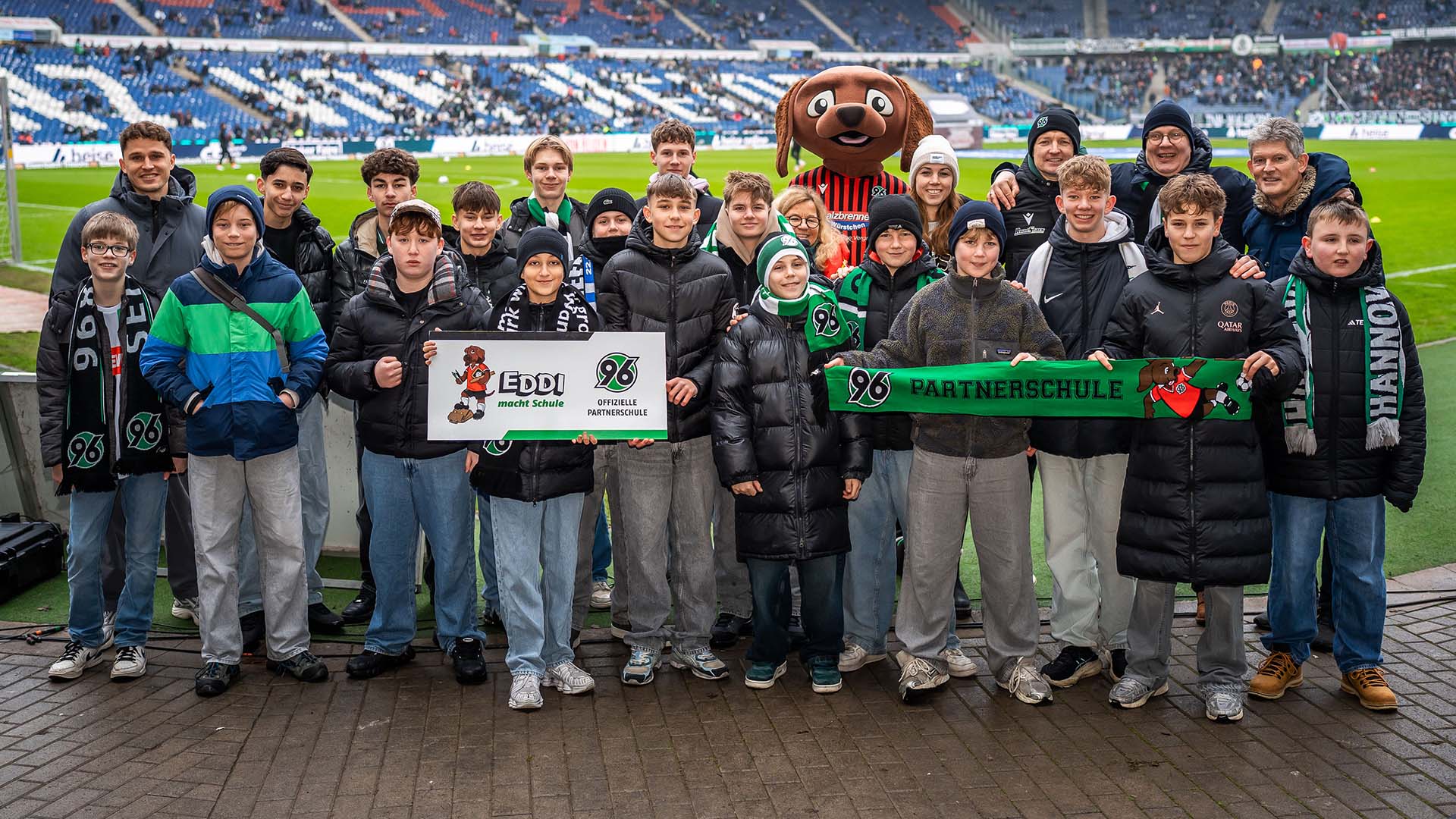 Eine Partnerschule posiert mit der Plakette im Stadion.