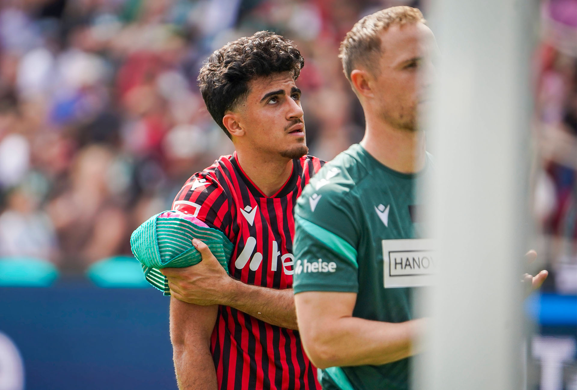 Husseyn Chakroun schaut nachdenklich leicht nach oben und hält sich einen Eisbeutel an die rechte Schulter.