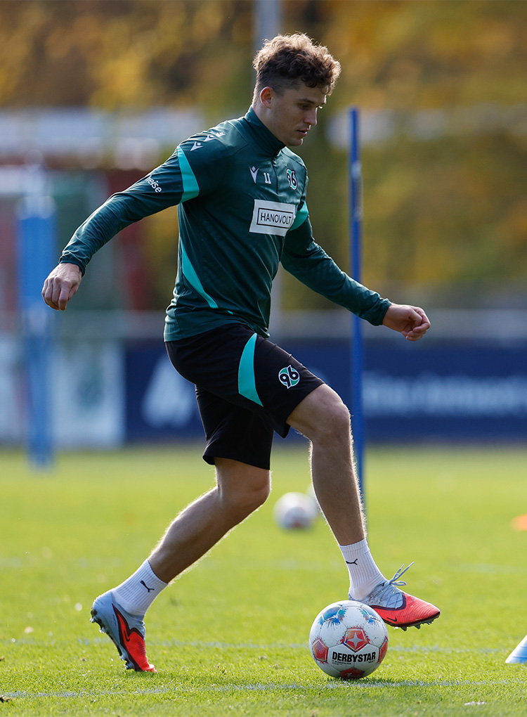 Seitliche Ganzkörperaufnahme von Benedikt Pichler am Ball im Training.