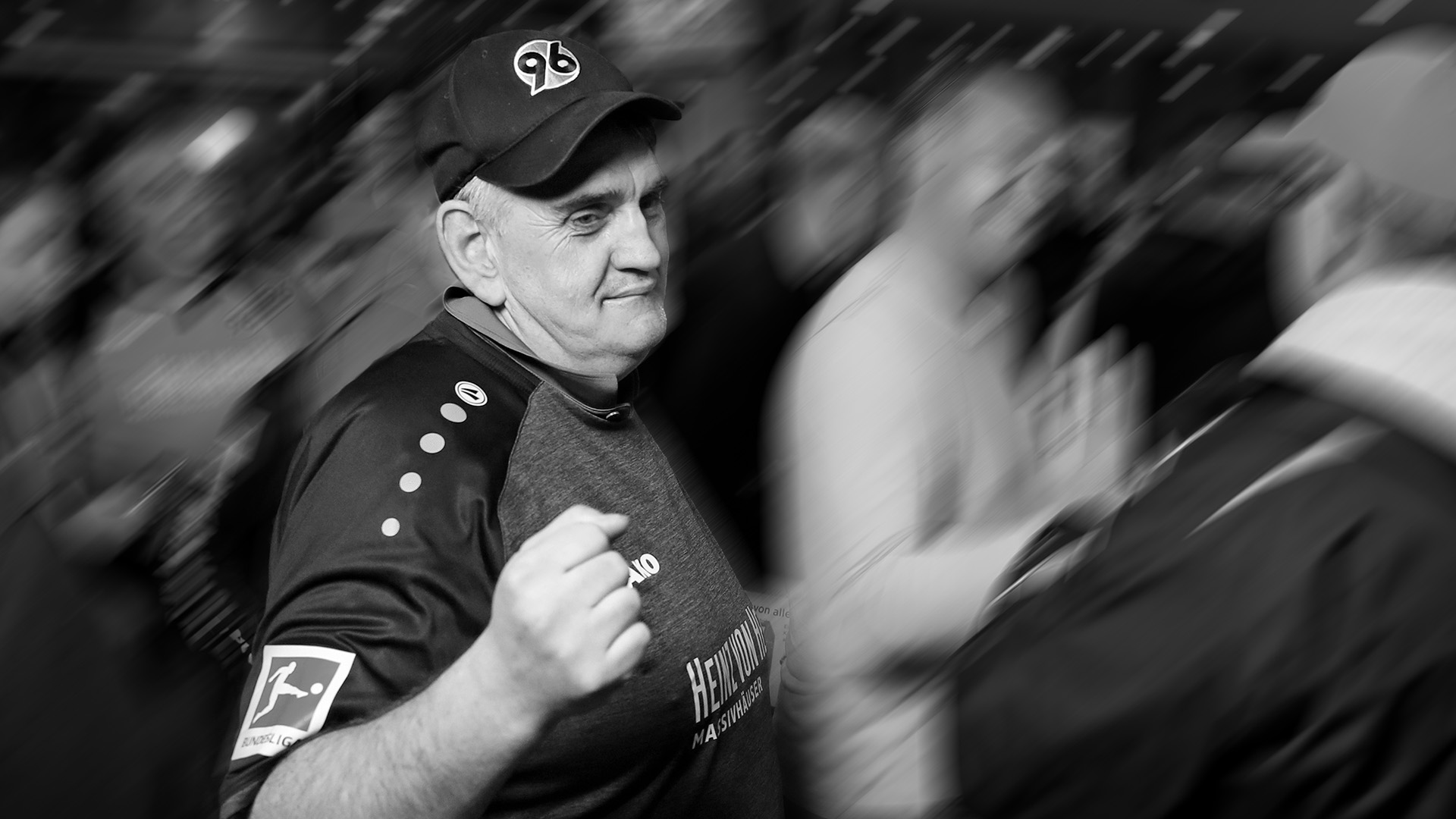 Schwarz-weißes Bild von 96-Fan Popcorn-Olaf in einem älteren 96-Trikot und mit 96-Cap.