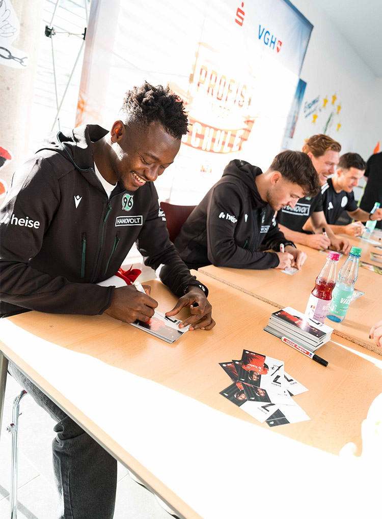 der 96-Profi Mustapha Bundu schreibt strahlend Autogramme.