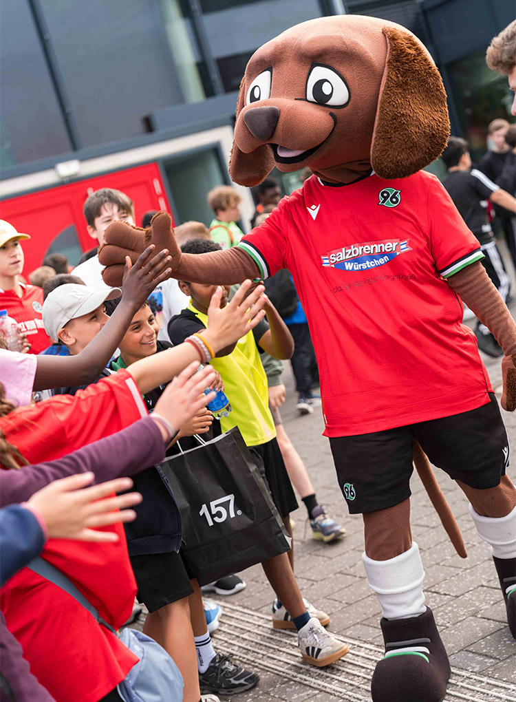 96-KIDS-Maskottchen EDDI klatscht mit Kindern ab.