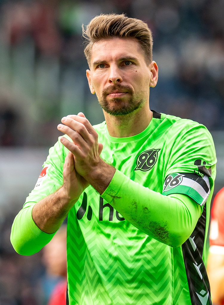 Ron-Robert Zieler hat die Hände vor der Brust, klatscht und blickt etwas nachdenklich in Richtung der Fans.