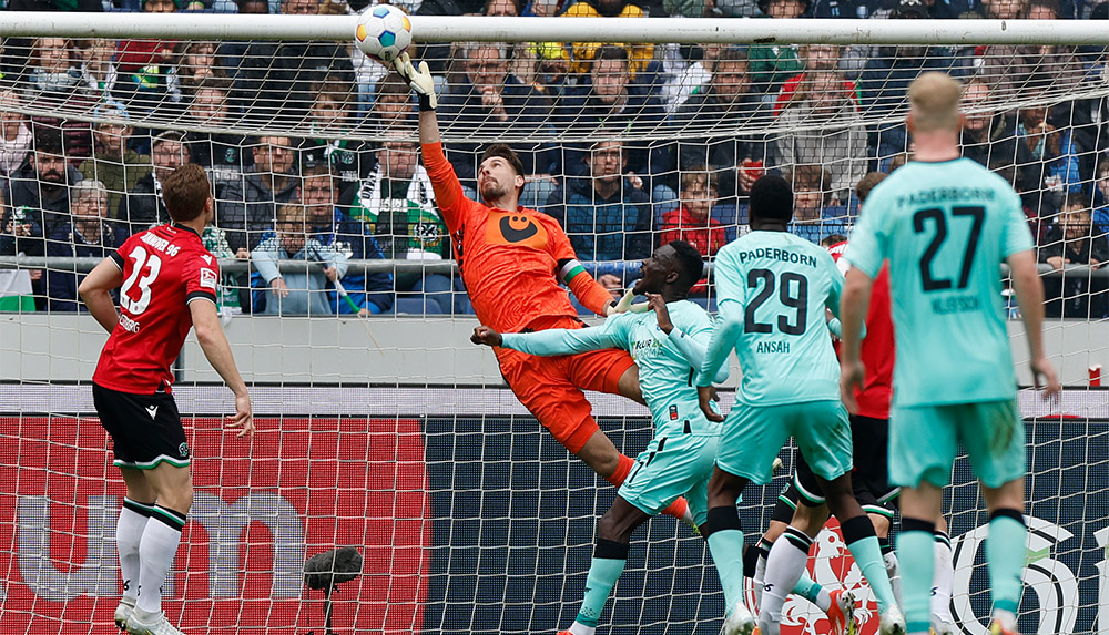 Ron-Robert Zieler wehrt den Ball kurz vor der Latte ab, davor stehen mehrere Spieler von Hannover und vom SC Paderborn.