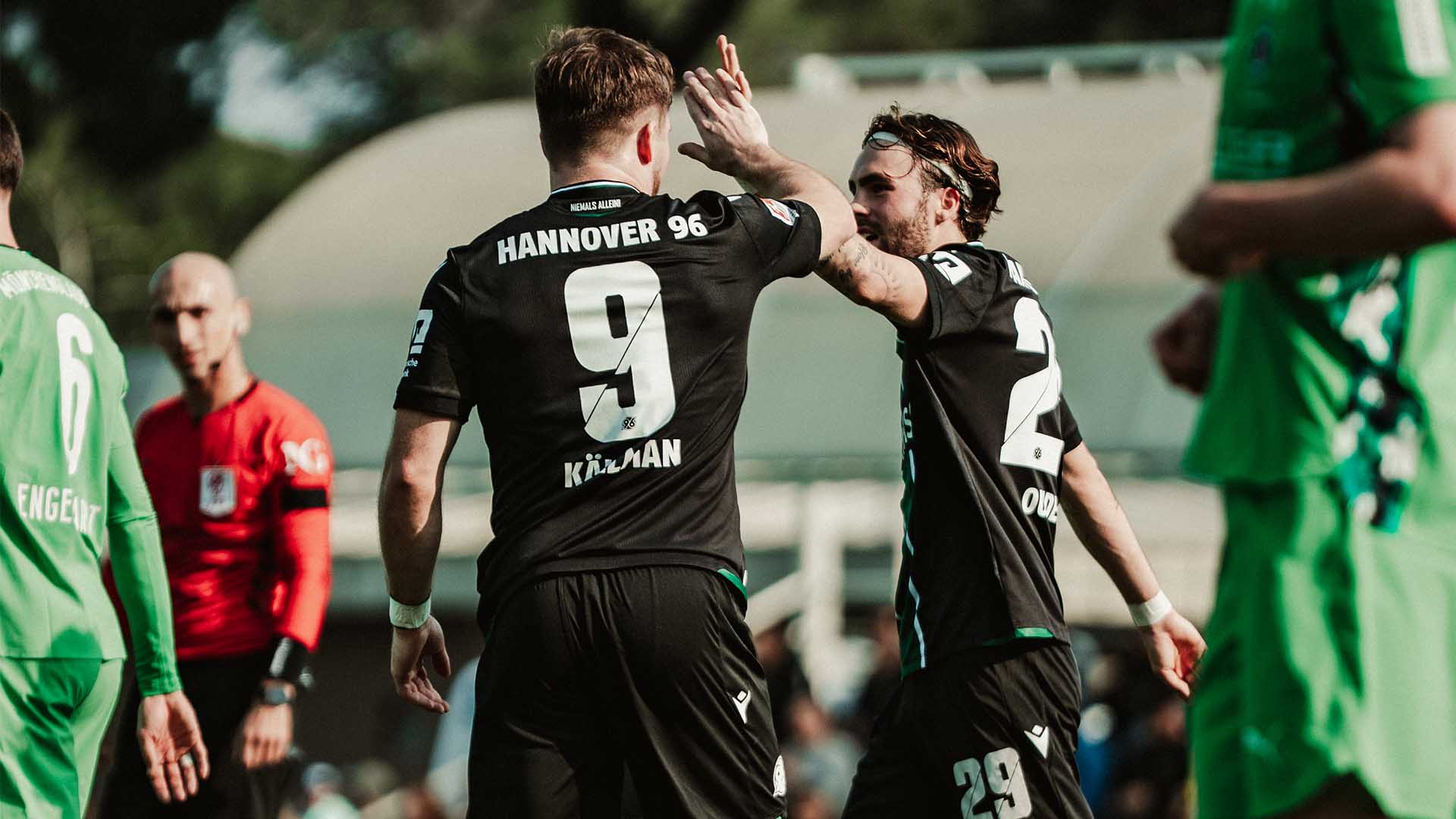 Zwei 96-Profis im schwarzen Trikot geben sich ein High-Five.