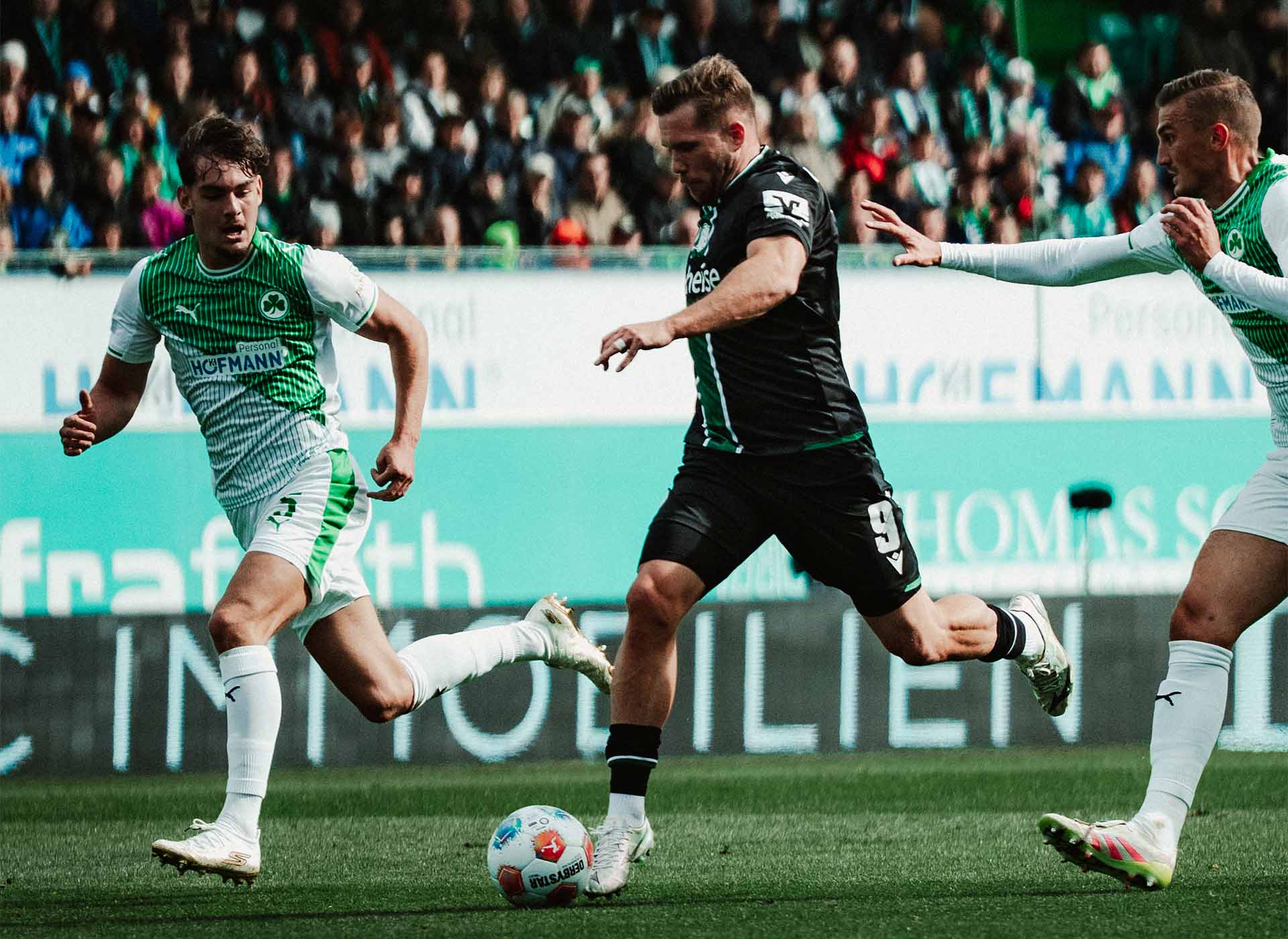 Benjamin Källman im Laufduell mit zwei Fürthern am Ball.