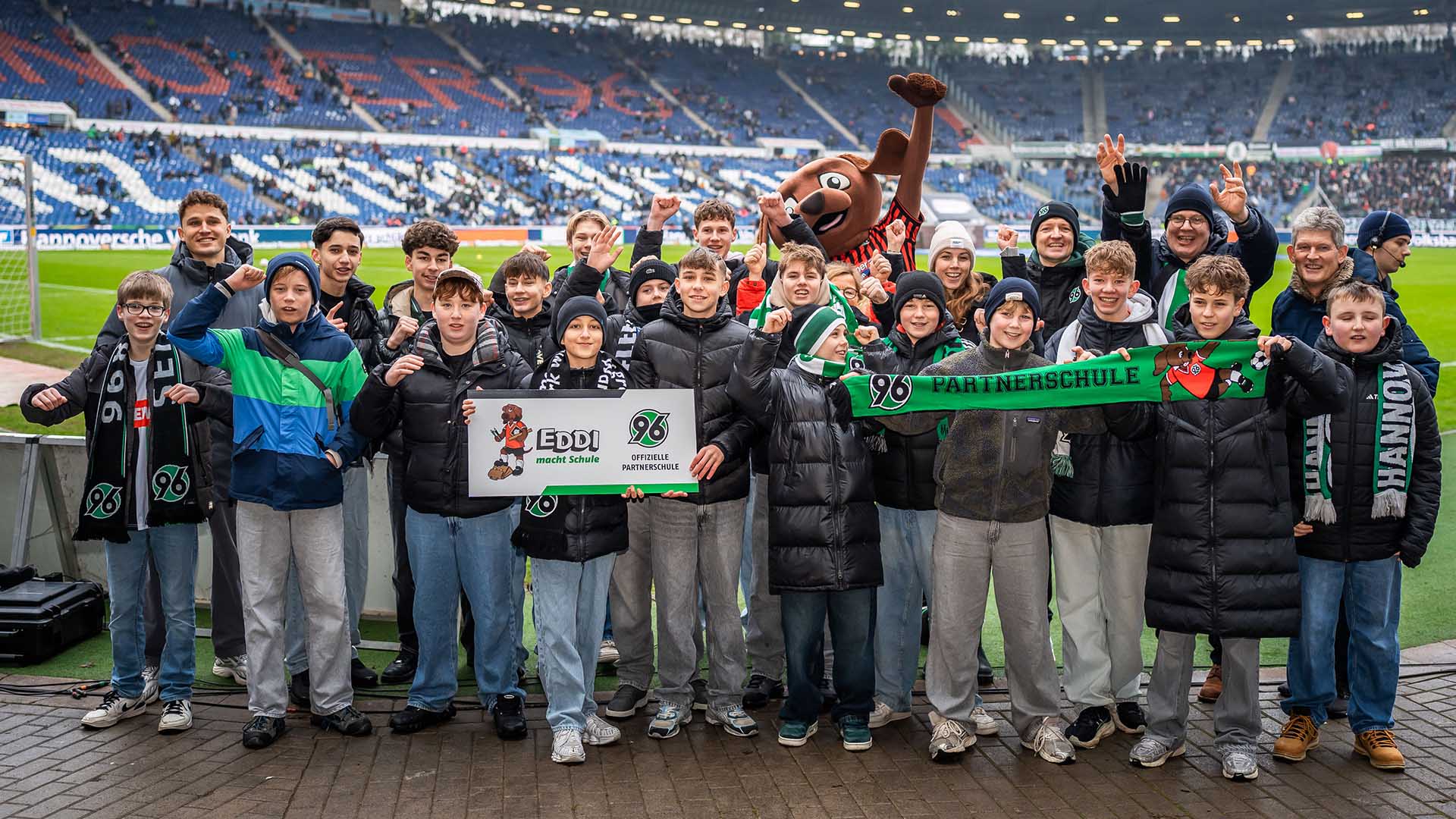 Eine Partnerschule posiert mit der Plakette im Stadion.