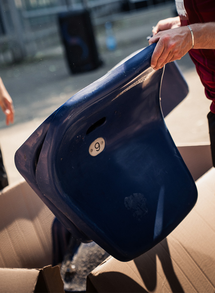 Eine blaue Sitzschale wird in der Hand gehalten.