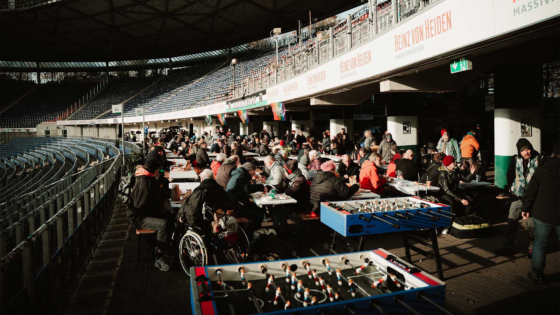 Blick in die Arena, wo zahlreiche Menschen an Tischen sitzen und essen.
