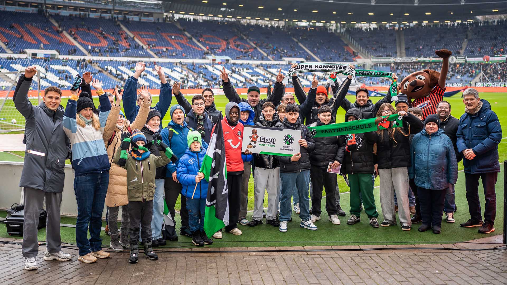 Eine Partnerschule posiert mit der Plakette im Stadion.