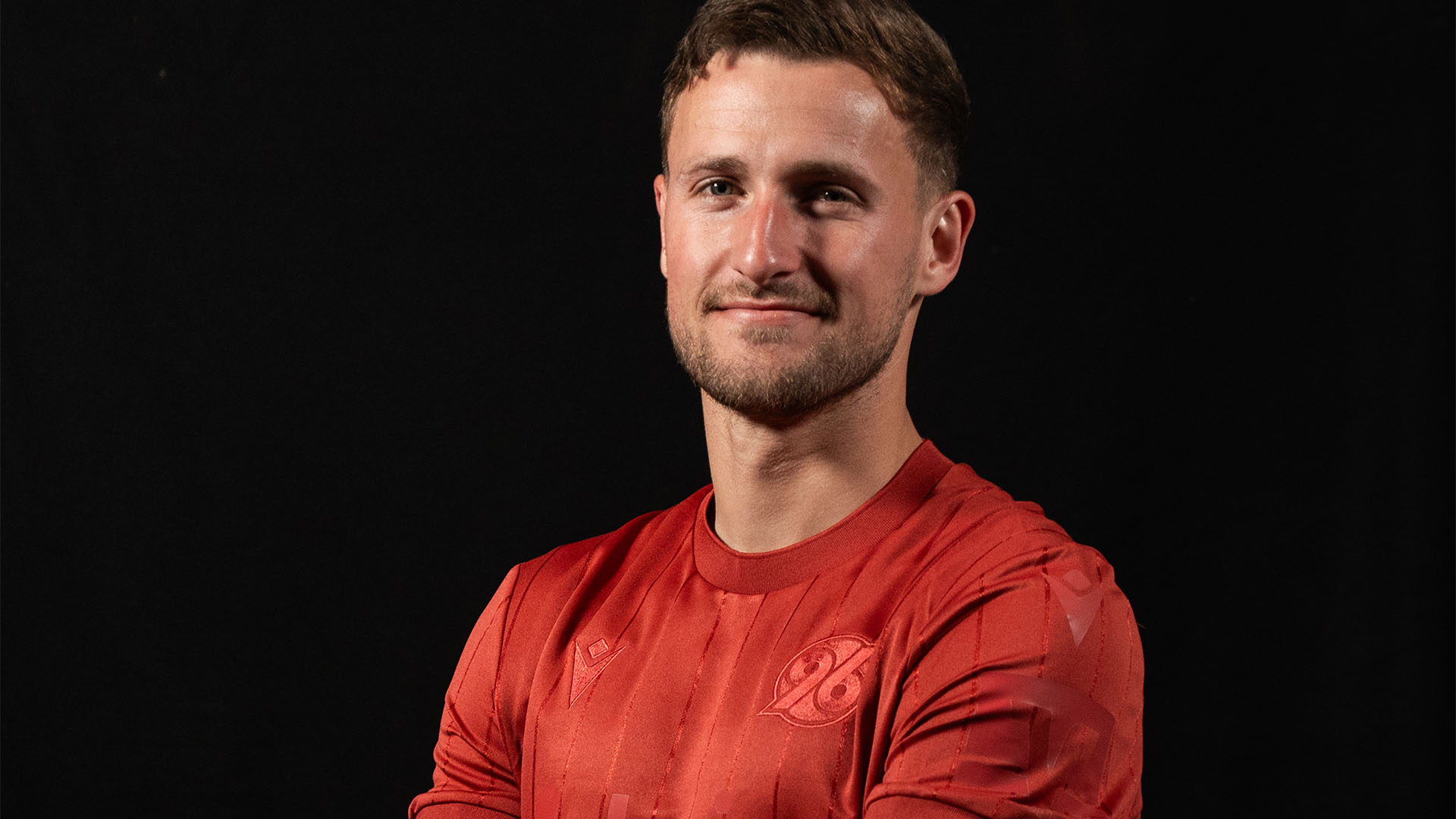 Enzo Leopold mit verschränkten Armen im Jubiläumstrikot.