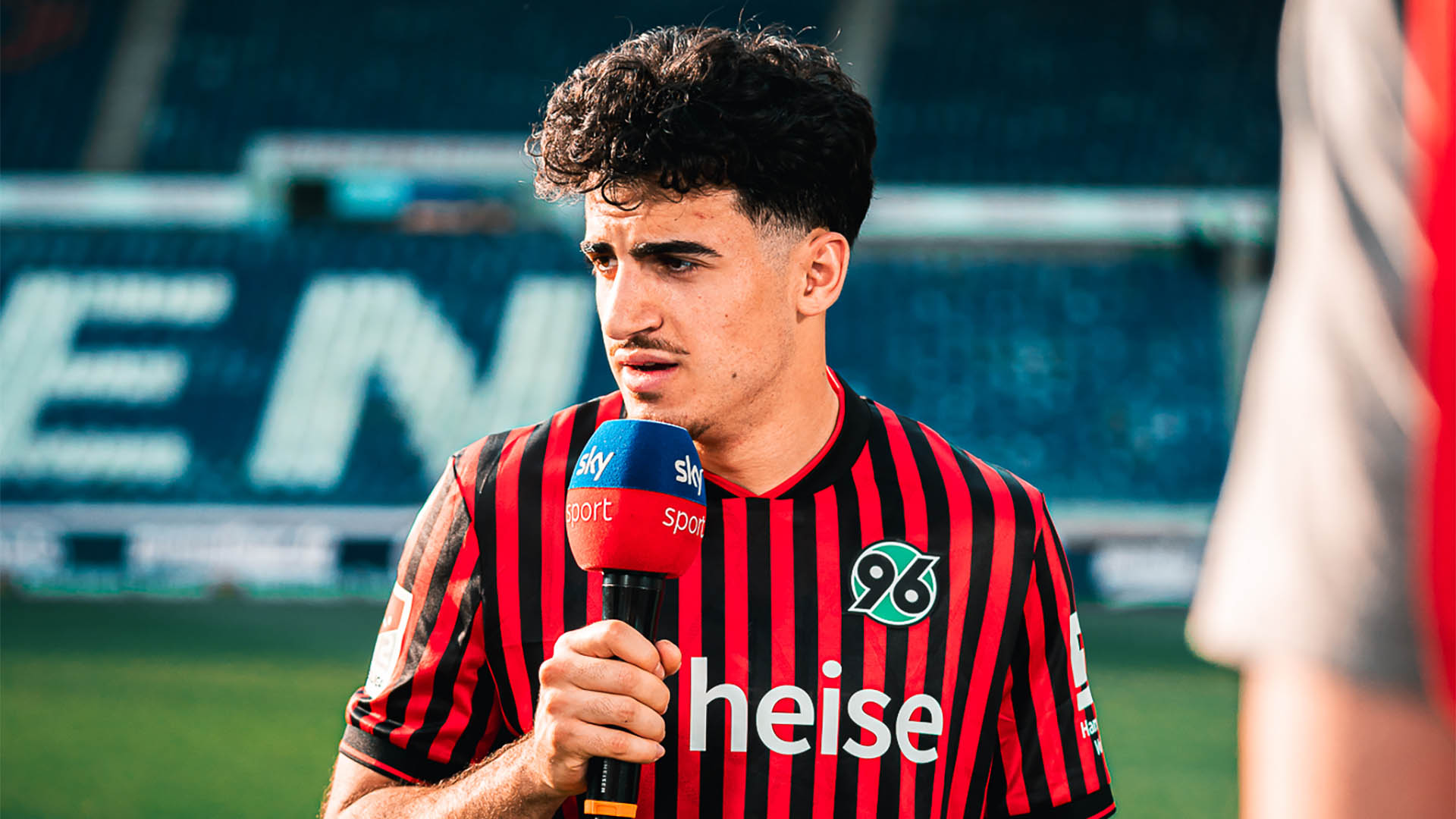Husseyn Chakroun im Heimtrikot am Sky-Mikrofon.