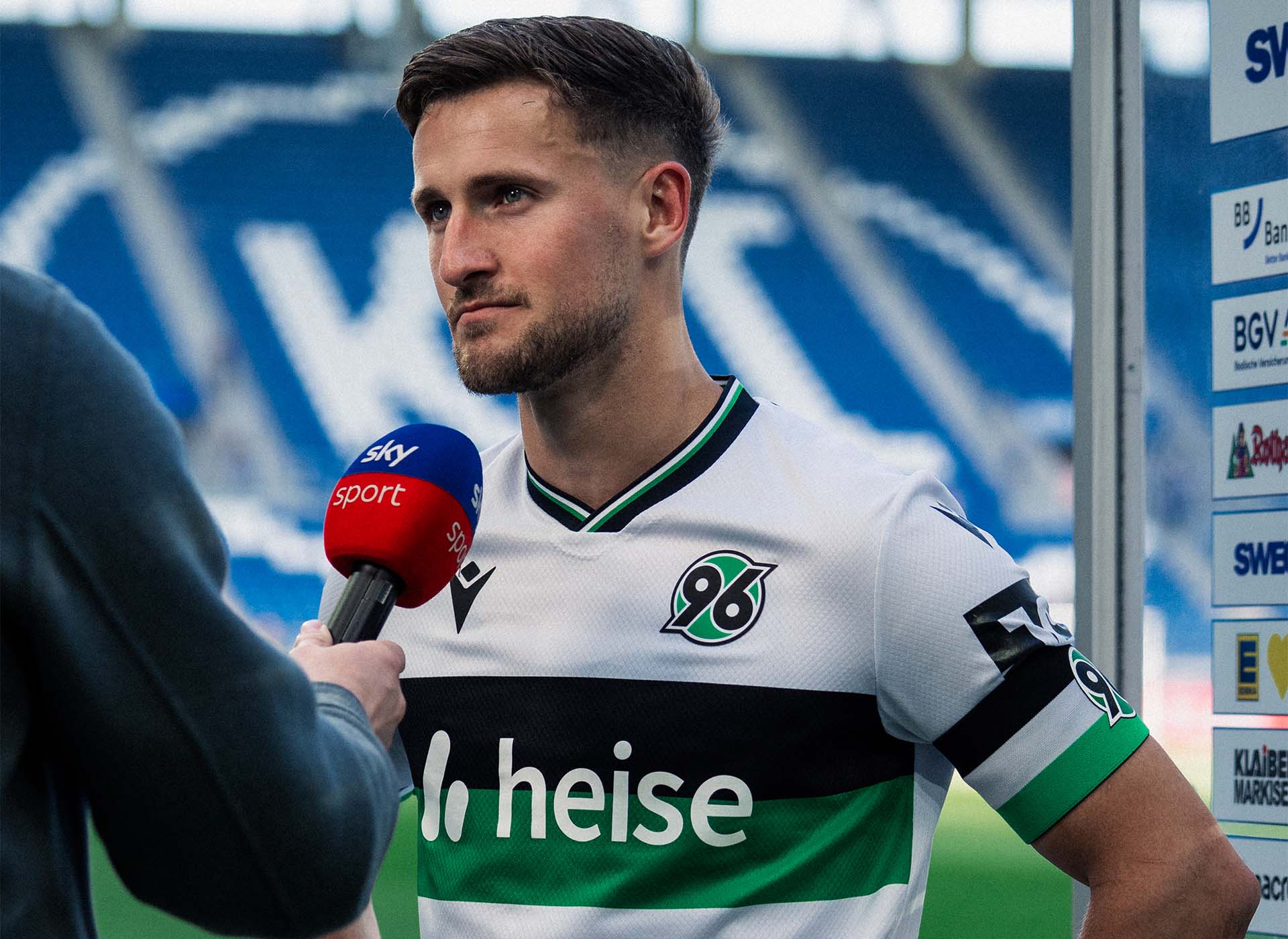 Enzo Leopold im weißen Trikot am Sky-Mikrofon.