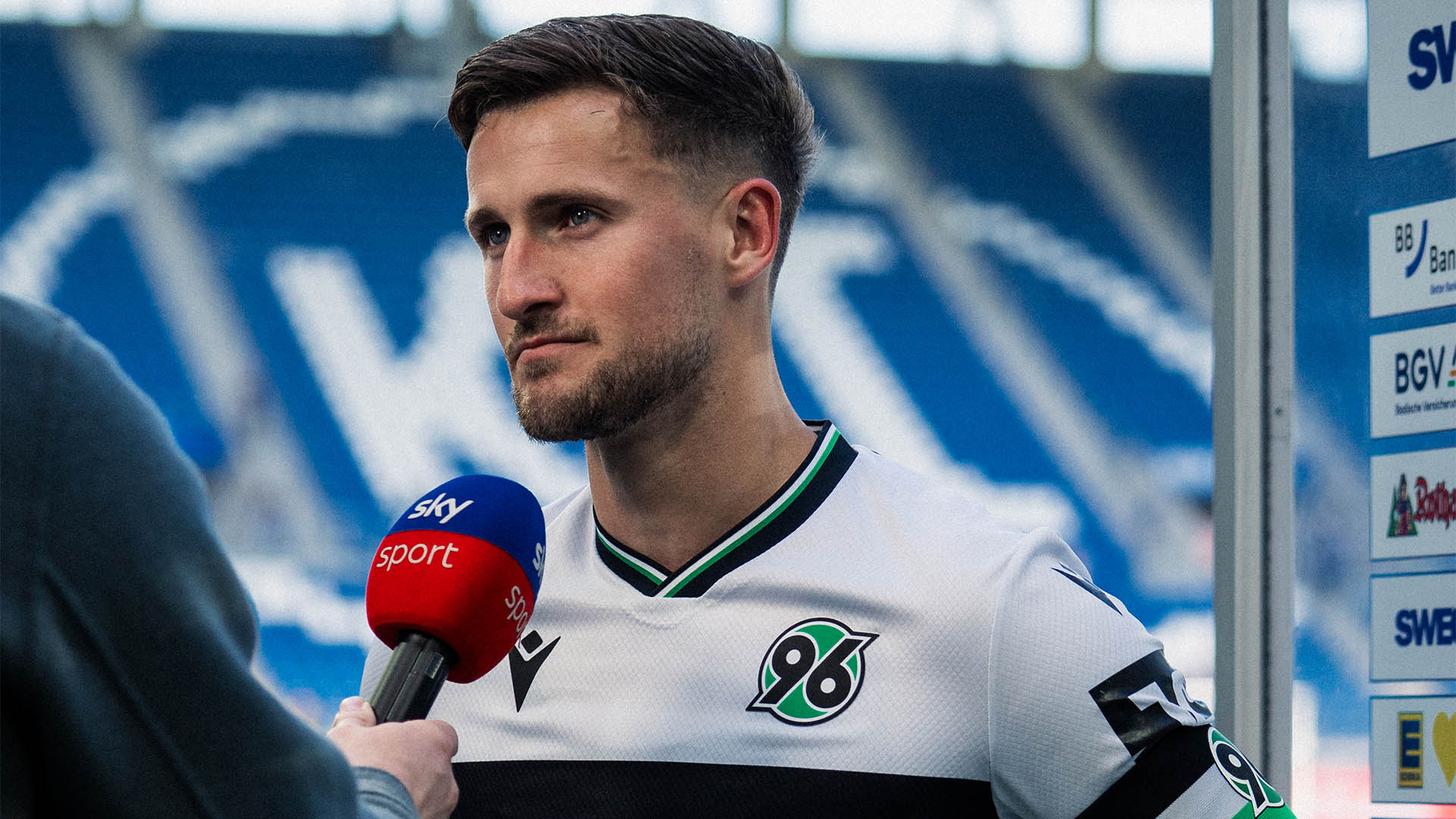 Enzo Leopold im weißen Trikot am Sky-Mikrofon.