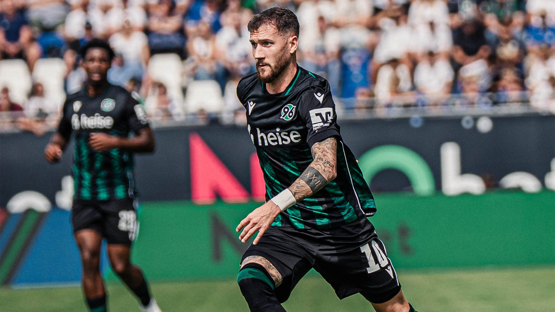 Der 96-Spieler Marcel Hartel im schwarz-grünen Auswärtstrikot am Ball.