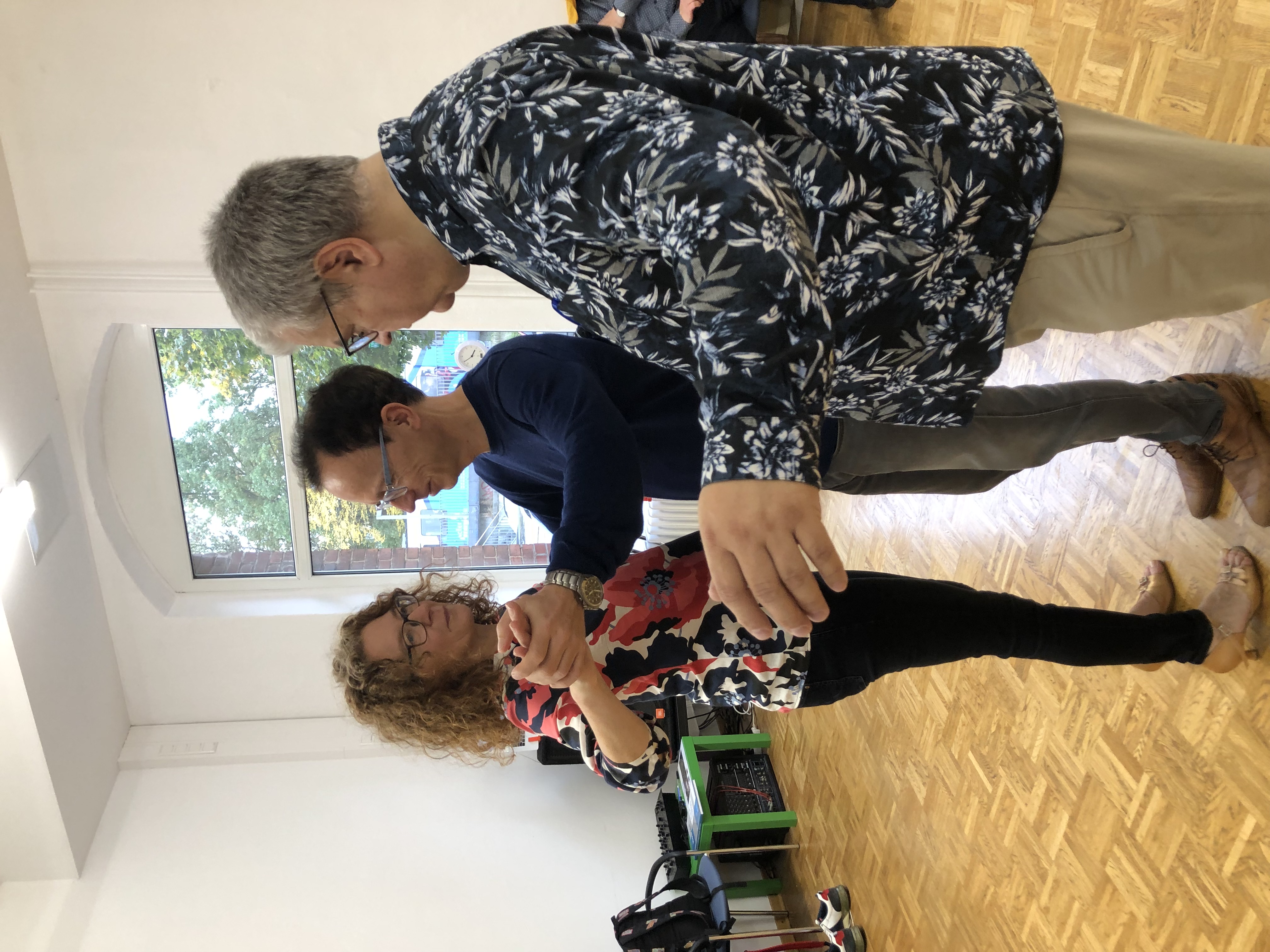 zwei Menschen tanzen und einer guckt zu