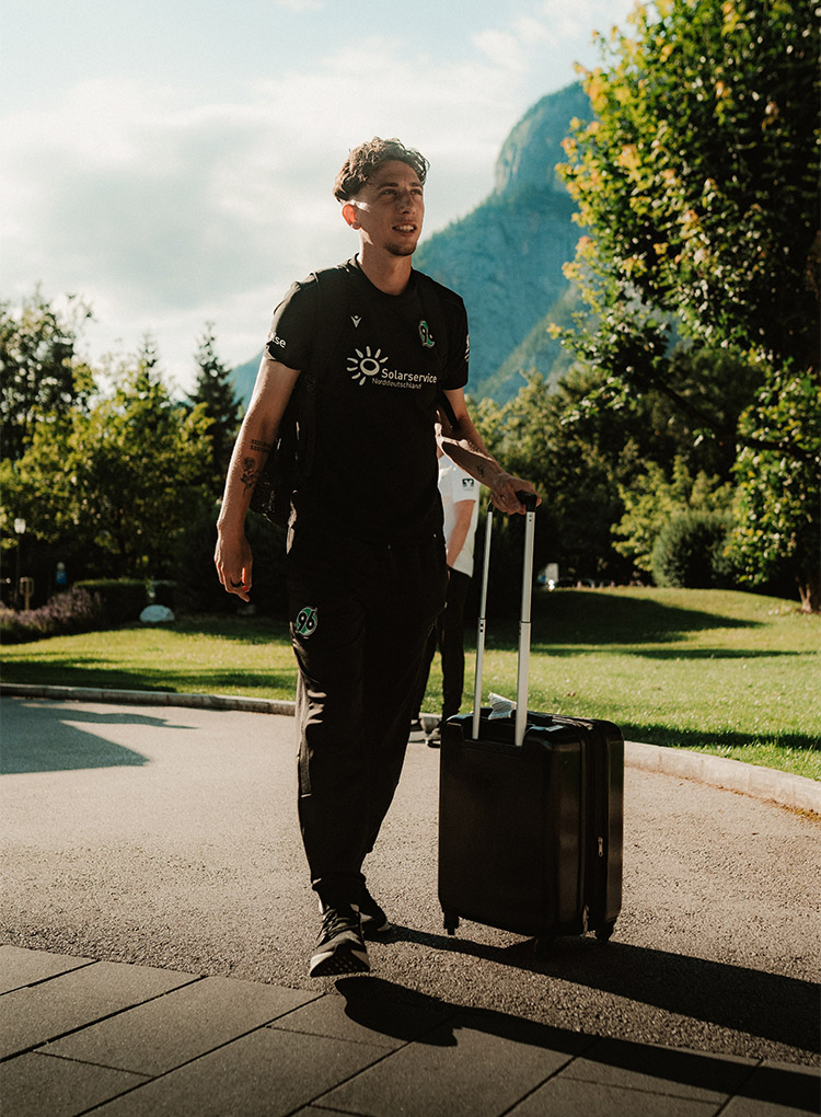Jannik Rochelt zieht seinen Koffer zum Hotel, im Hintergrund ist ein Berg. 
