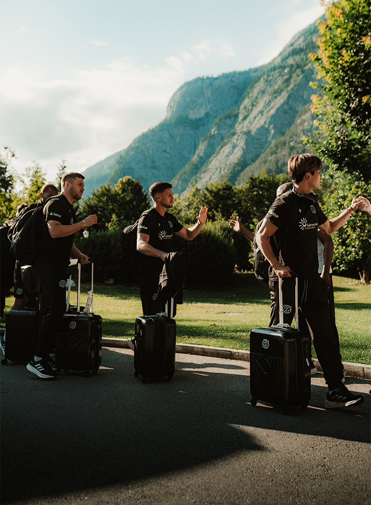 Benjamin Källman, Enzo Leopold und Hayate Matsuda kommen mit ihren Koffern an, im Hintergrund ist ein Berg.