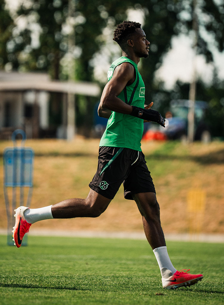 Mustapha Bundu läuft in Trainingskleidung, an der rechten Hand trägt er eine schwarze Schiene.