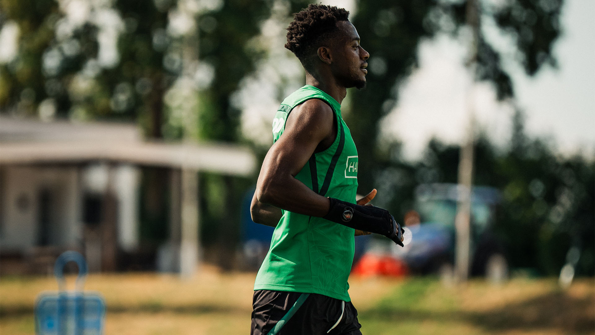 Mustapha Bundu läuft in Trainingskleidung, an der rechten Hand trägt er eine schwarze Schiene.