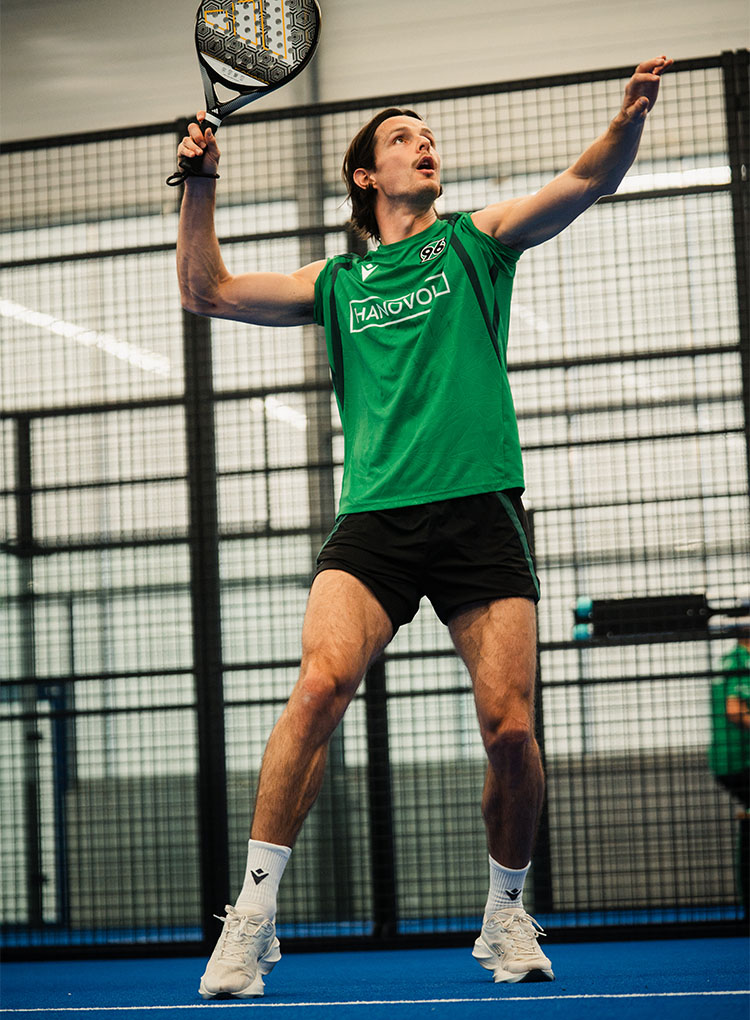 Ein Spieler schlägt mit einem Padel-Tennisschläger auf. 