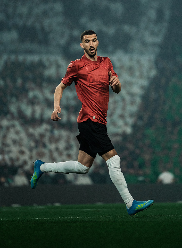 Waniss Taibi läuft im Jubiläumstrikot, im Hintergrund eine schwarz-weiß-grüne Choreo. 