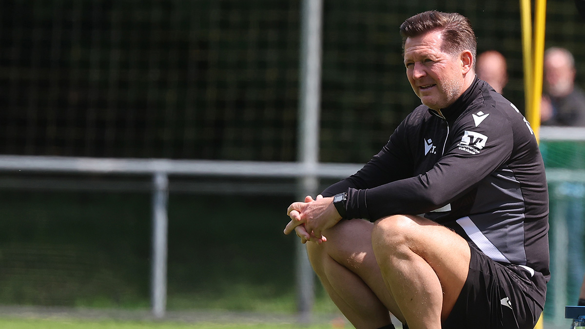 Cheftrainer Christian Titz beim Training auf einem Ball sitzend.