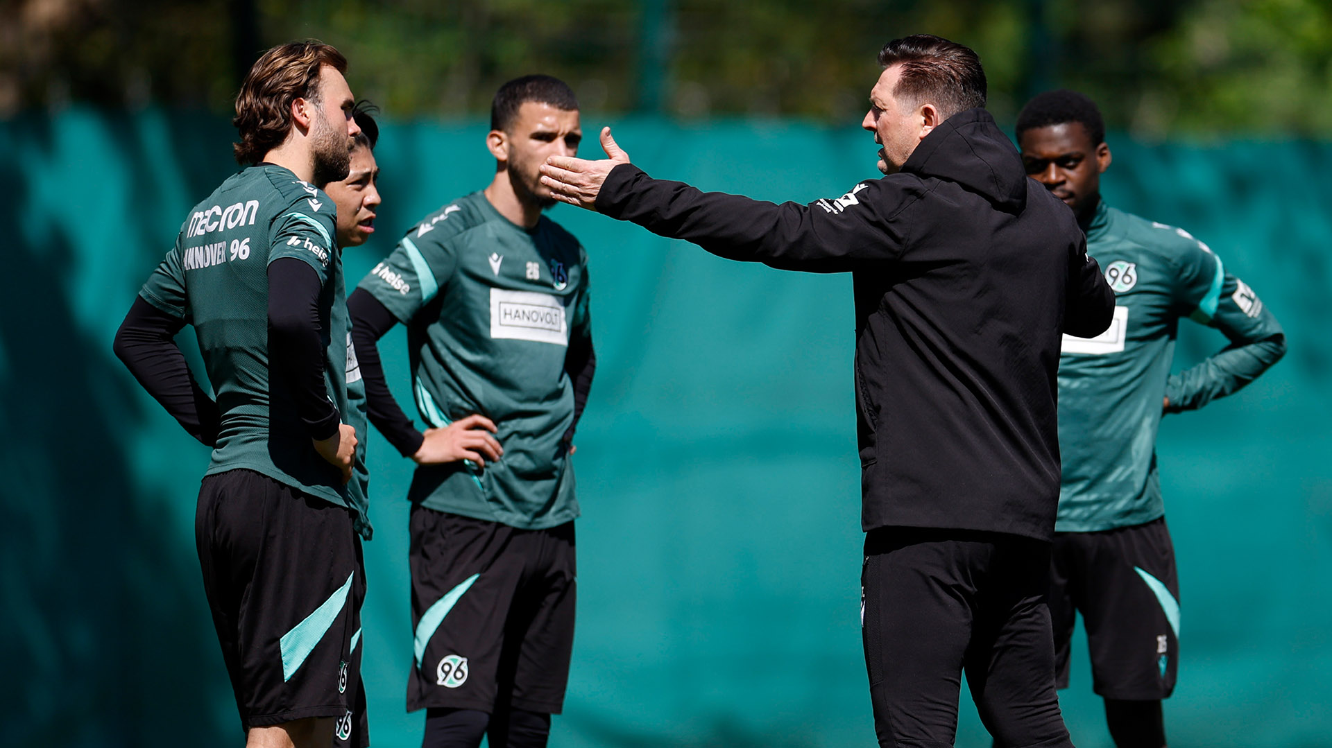 Christian Titz gestikulierend im Gespräch mit vier Spielern.