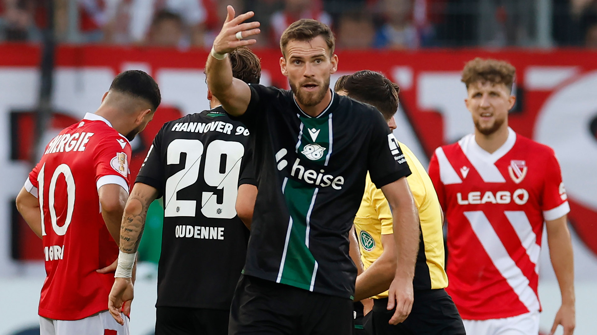 Boris Tomiak schaut energisch und deutet mit dem rechten Arm, im Hintergrund Kolja Oudenne und einige Cottbus-Spieler.