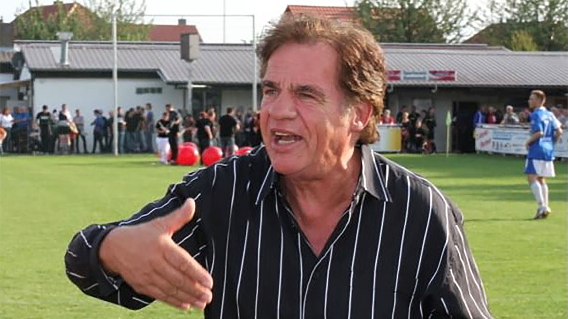 96-Traditionsteamchef Frank Obermeyer steht auf einem Fußballplatz und gestikuliert mit der rechten Hand.