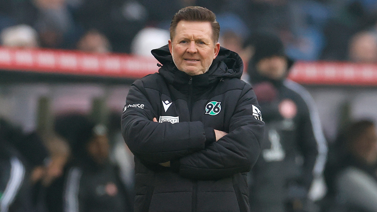 Christian Titz steht in 96-Jacke mit verschränkten Armen an der Seitenlinie.