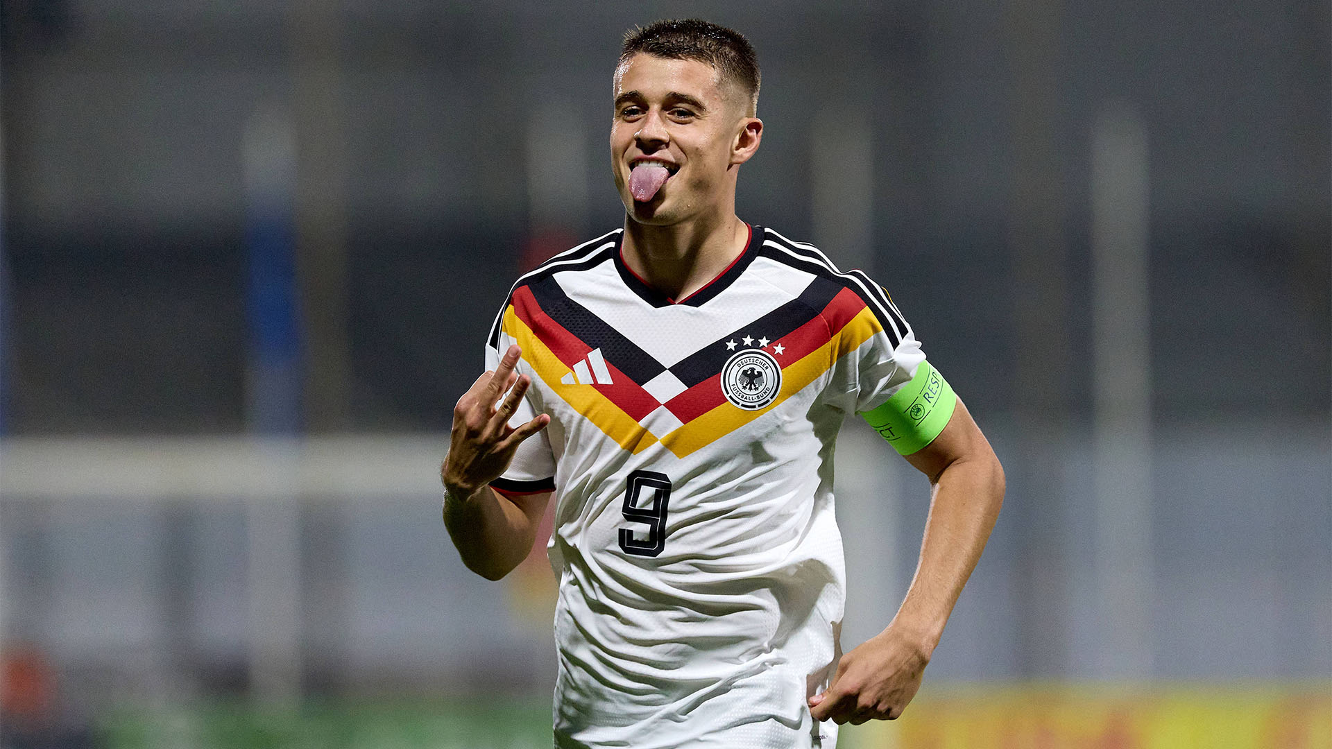 U21-Stürmer Nicolo Tresoldi im DFB-Trikot jubelt mit herausgestreckter Zunge und zeigt mit der rechten Hand drei Finger für drei Tore.