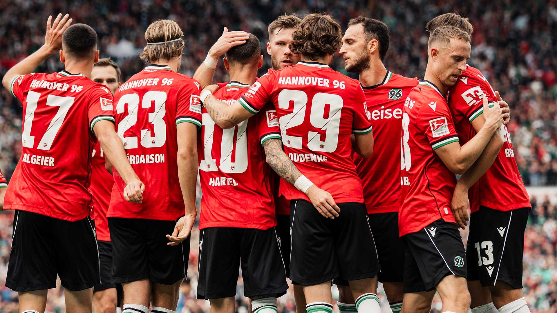 Einige 96-Spieler klatschen in Heimtrikots miteinander ab, die meisten sind von hinten zu sehen.