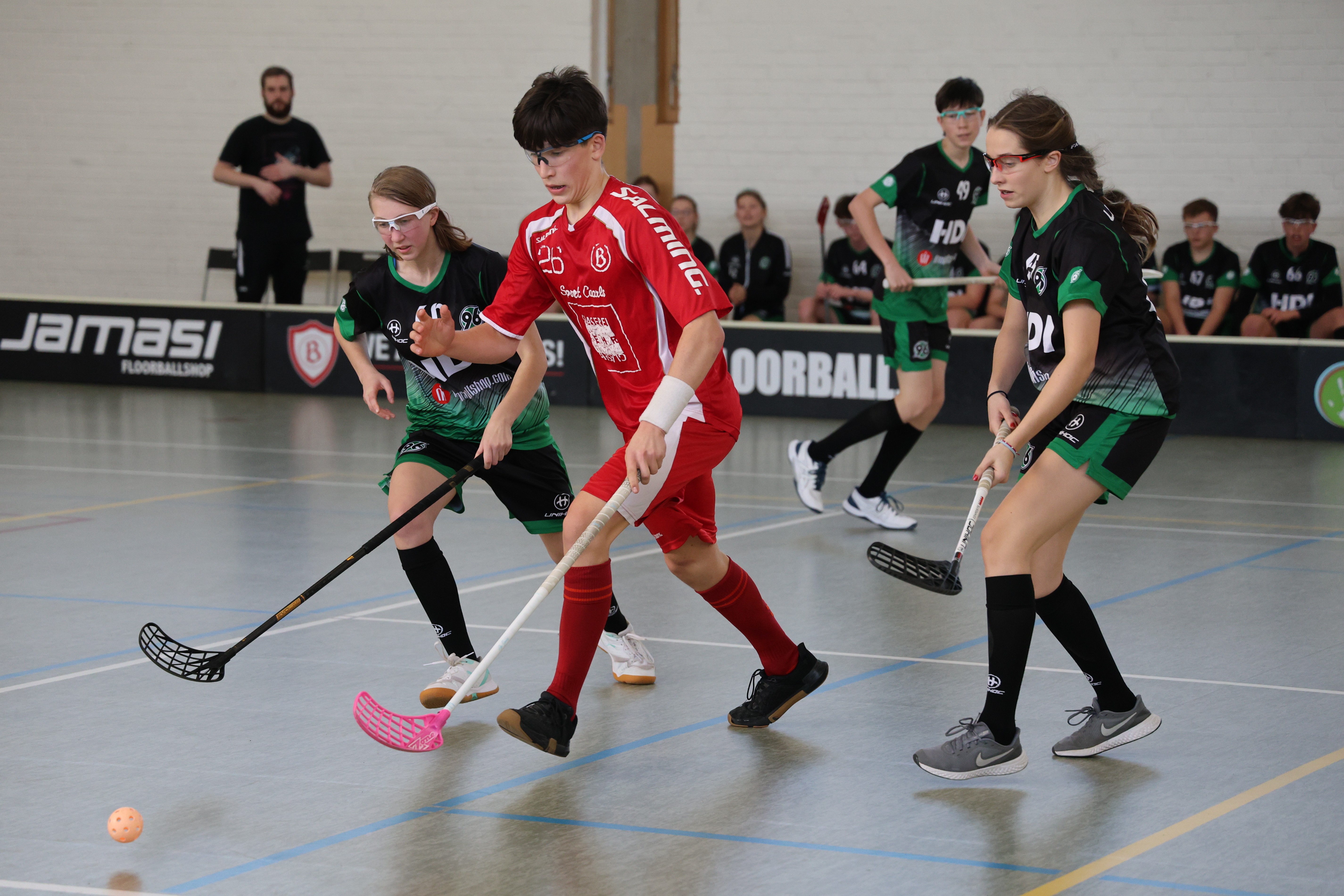 Drei SpielerInnen laufen zum Ball.