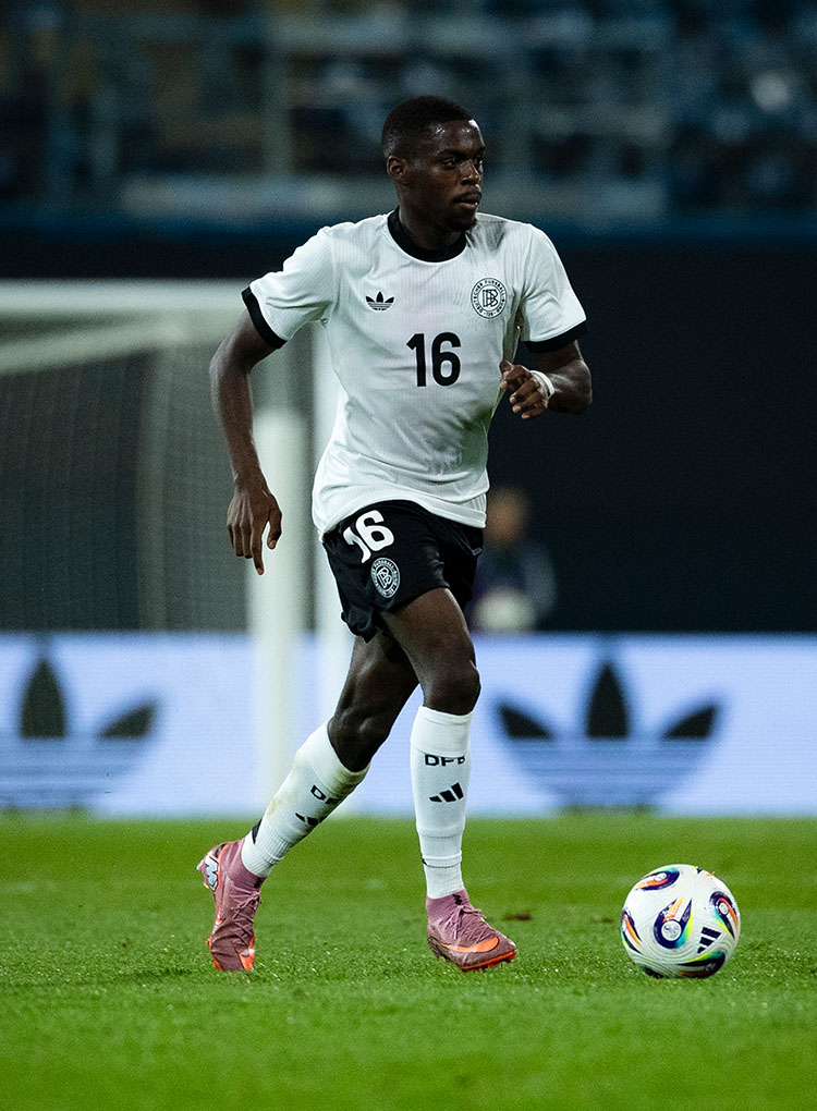 Ganzkörperaufnahme von Noel Aseko im DFB-Trikot am Ball.  