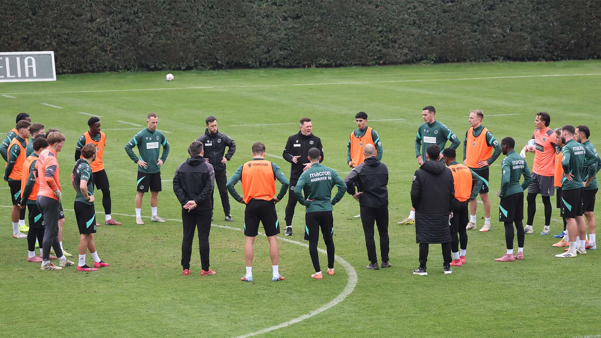 Christian Titz steht mit seiner Mannschaft im Kreis auf dem Trainingsplatz und erklärt etwas.