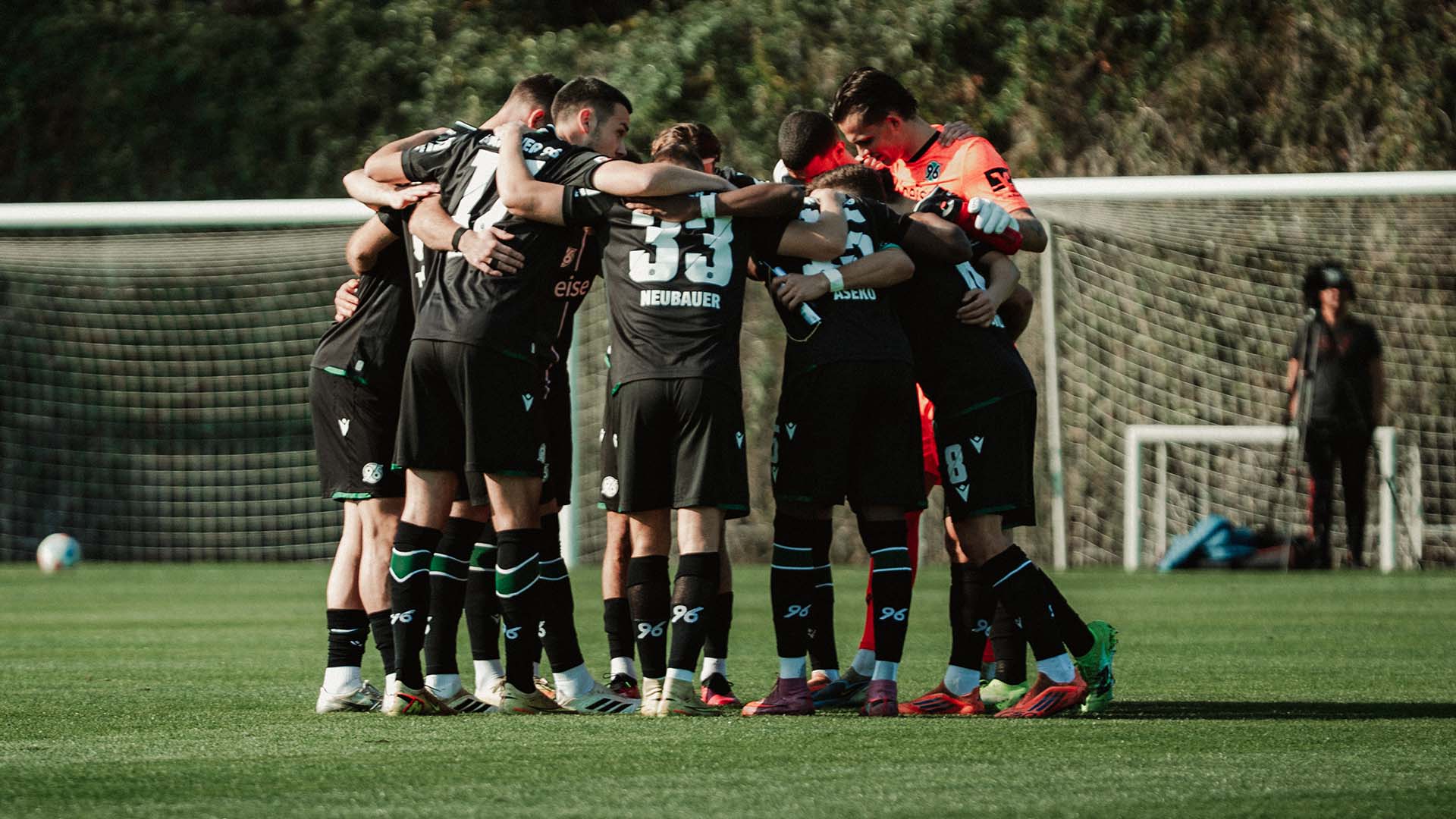 Die 96-Mannschaft steht in Auswärtstrikots in einem Kreis.