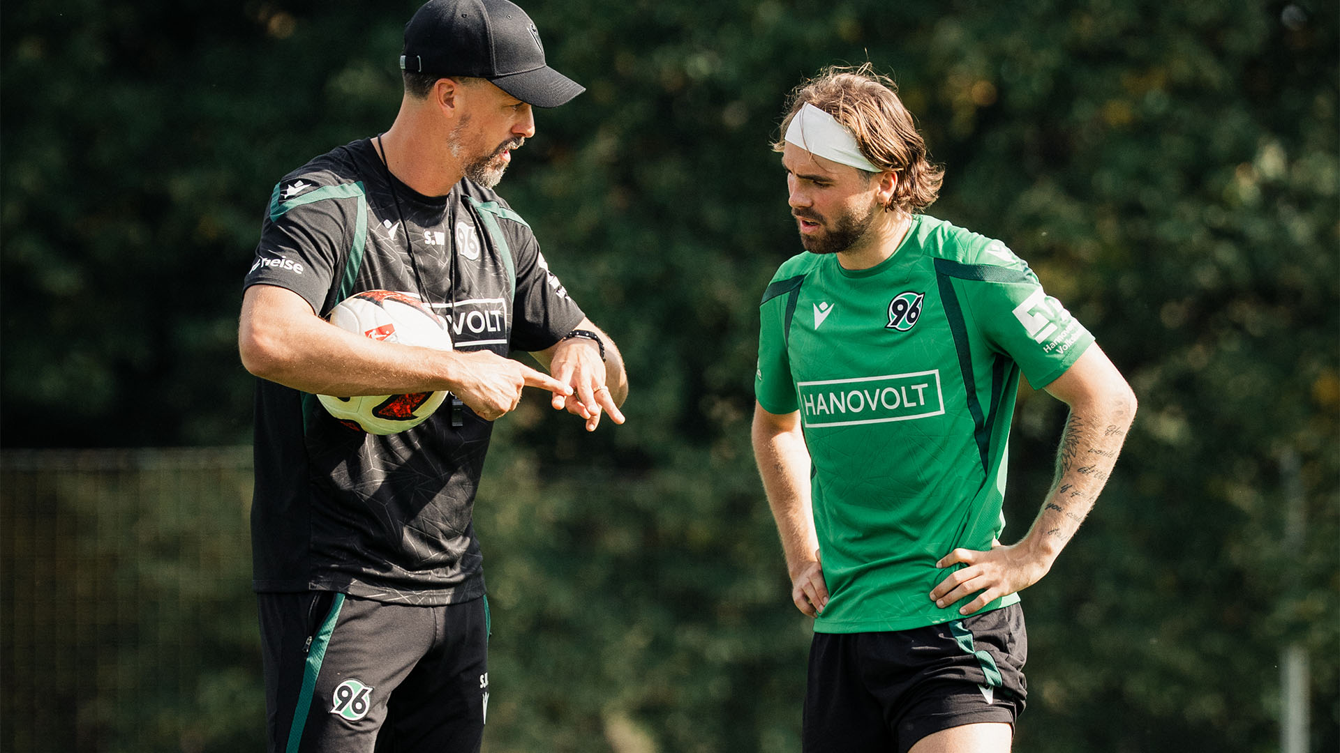 96-Trainer Sandro Wagner erklärt 96-Spieler Kolja Oudenne gestenreich etwas auf dem Trainingsplatz.