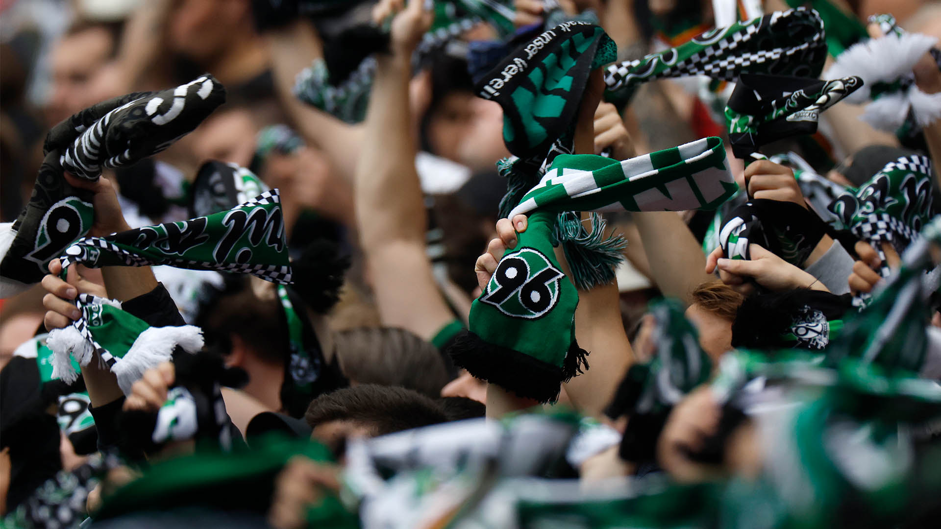 96-Fans schwenken 96-Schals, Gesichter sind nicht zu sehen.