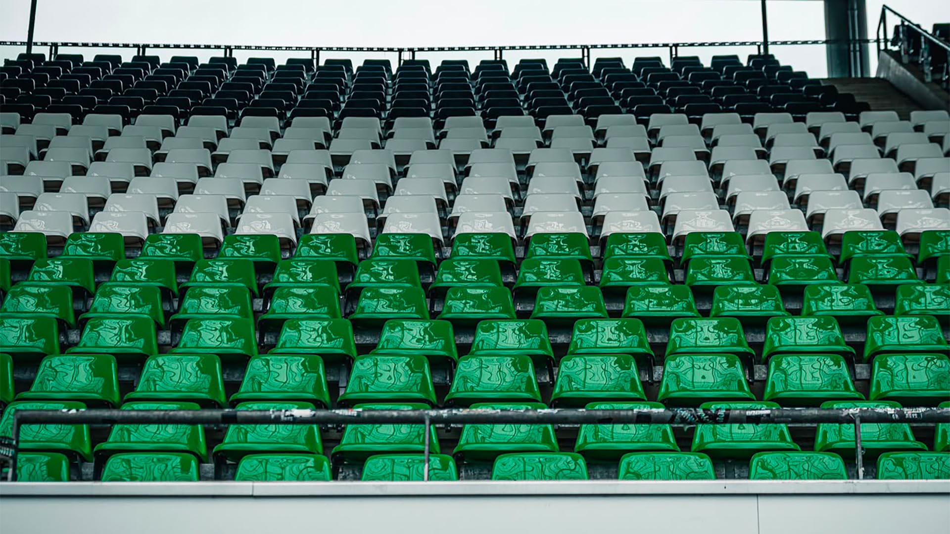 Schwarze, weiße und grüne Sitzschalen im Stadion.