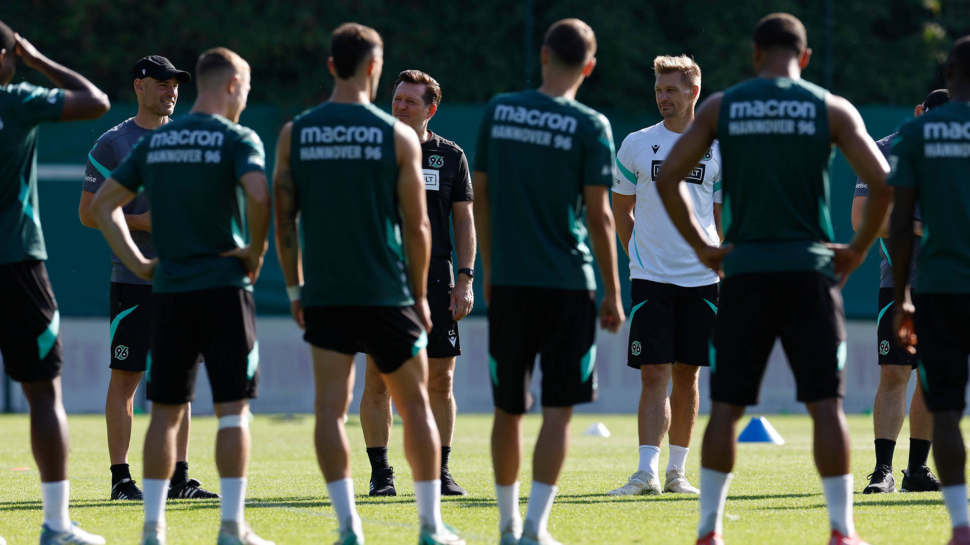 Kreis auf dem Platz: Felix Sunkel, Christian Titz und Michael Ratajczak sind von vorne zu sehen, einige Spieler von hinten. 