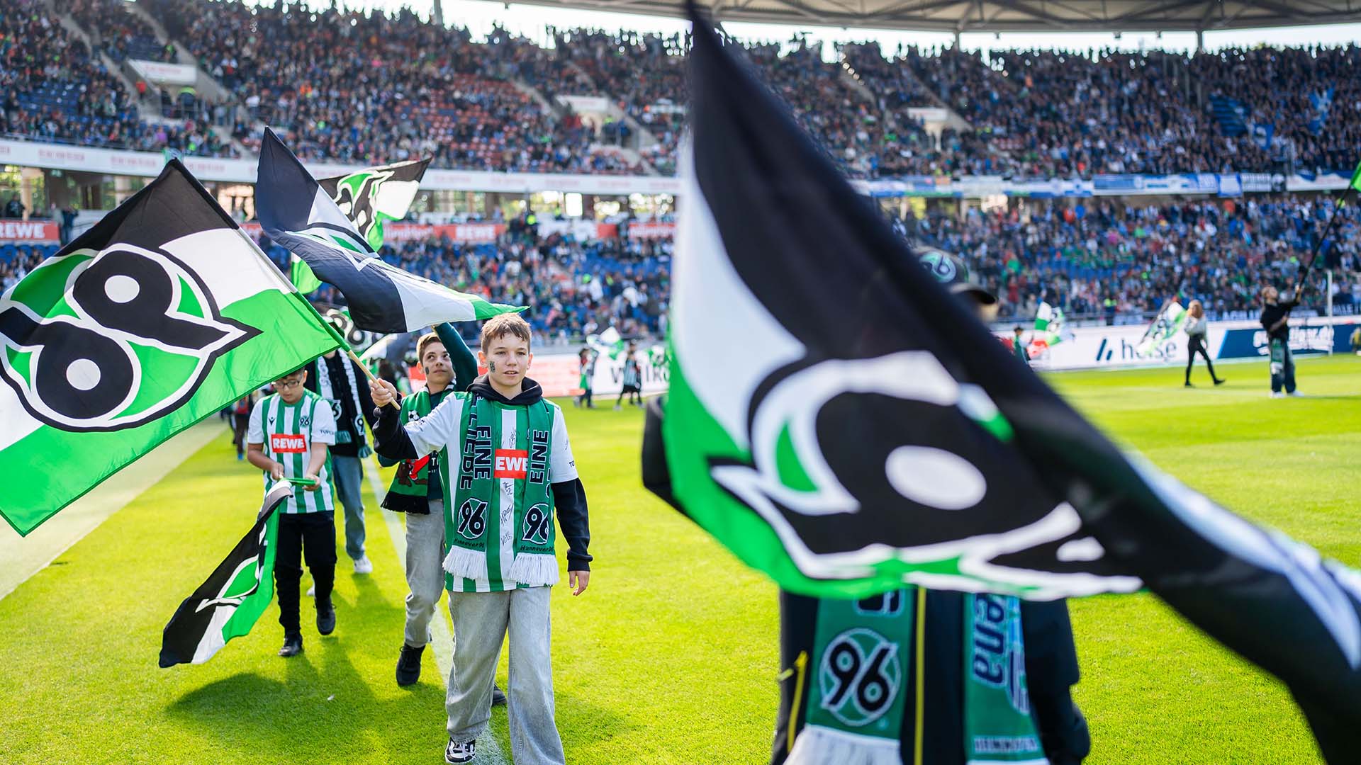 Kinder, die mit 96-Fahnen ins Stadion einlaufen.