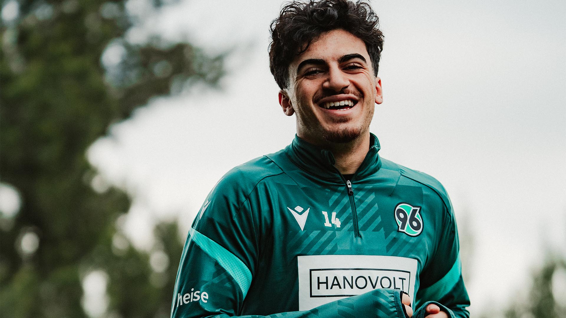 Husseyn Chakroun joggt in Trainingskleidung lachend auf die Kamera zu.