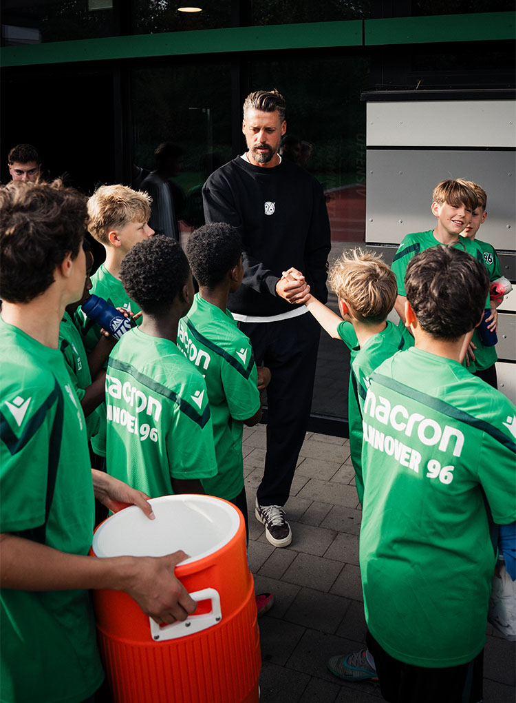 Sandro Wagner klatscht mit einer Gruppe von Kids in Trainingskleidung ab. (Foto: 96/Redaktion)