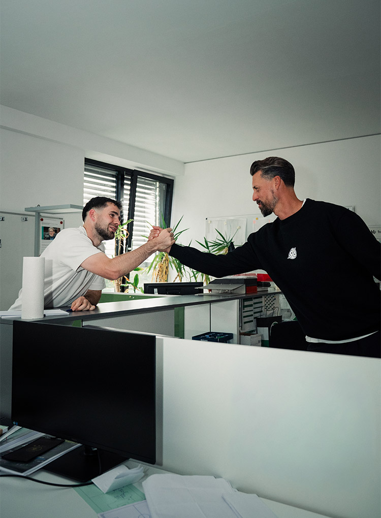 Sando Wagner schlägt drinnen über einem Tresen mit einem Trainer der Akademie ein. 