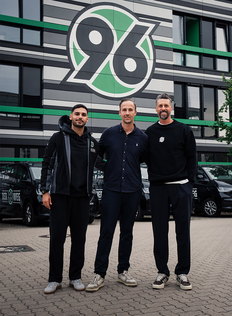 96-Cheftrainer Sandro Wagner, Co-Trainer Can Ünal und Akademiedirektor Julian Battmer stehen vor der 96-Akademie.