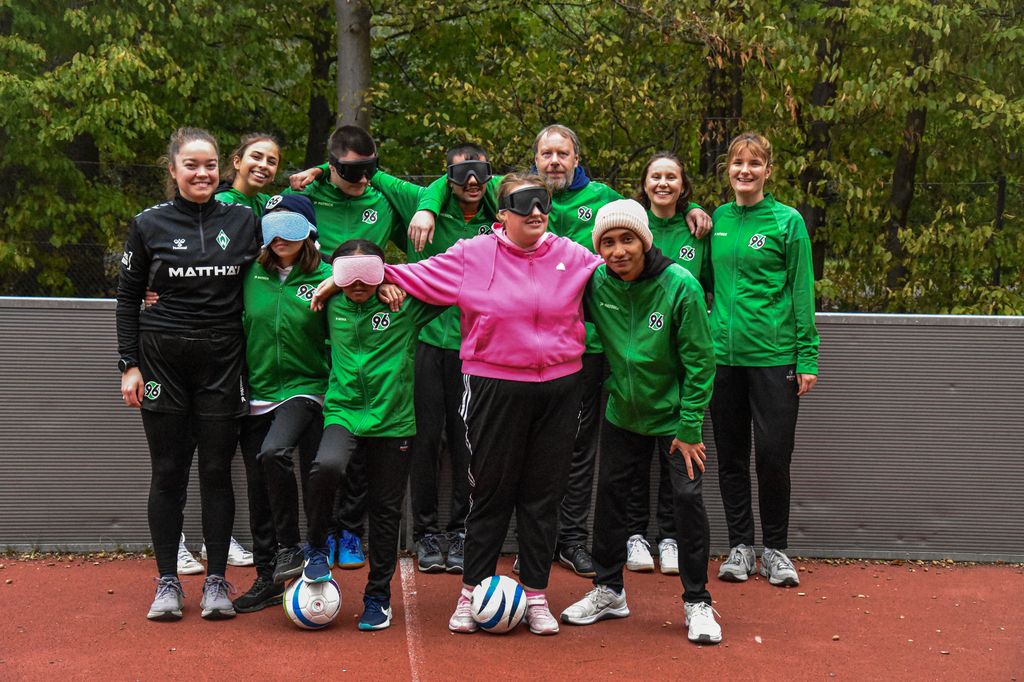 Die SpielerInnen lächeln mit 96-Trikots und Dunkelbrillen in die Kamera.