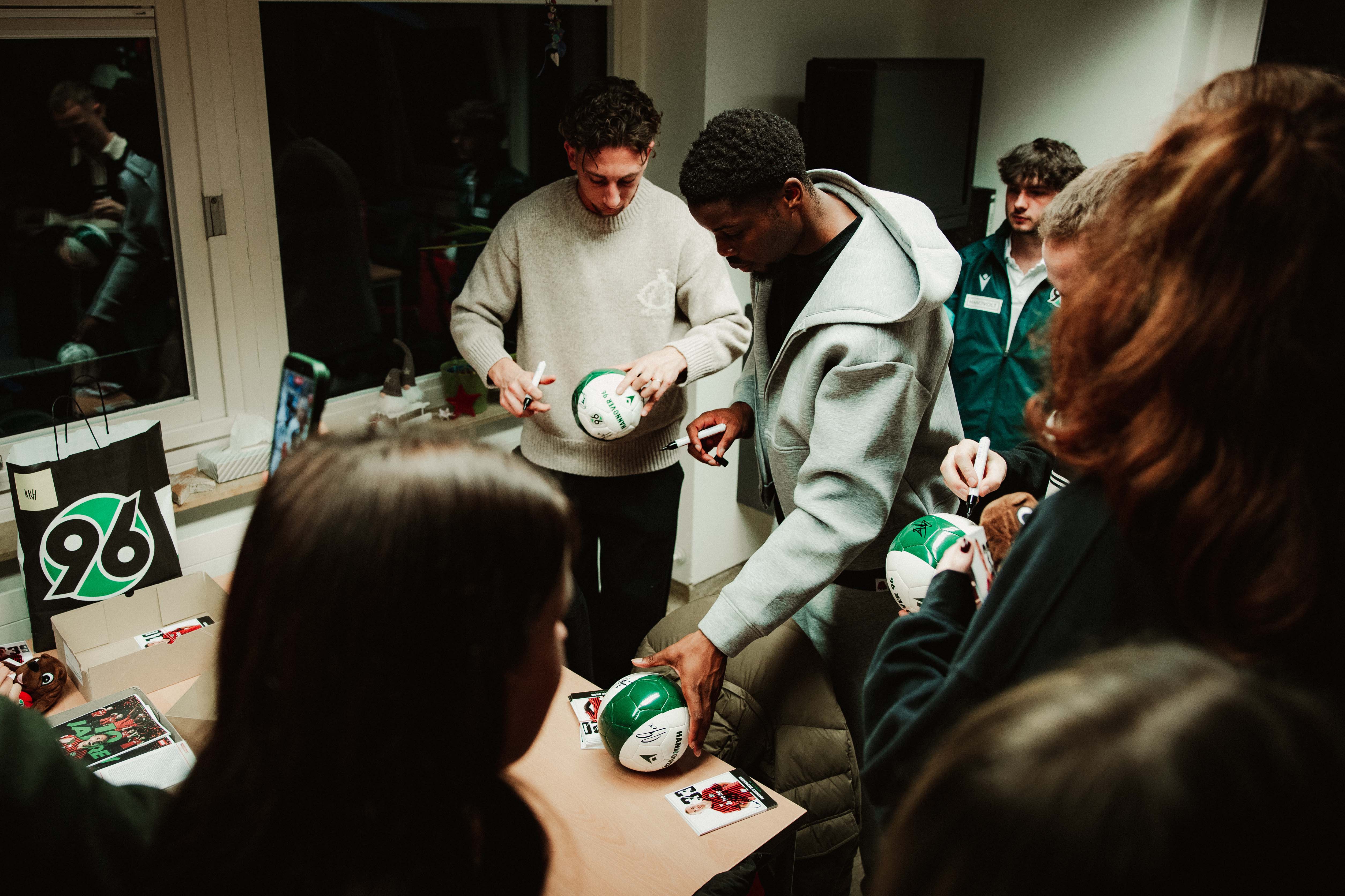 Die Profis unterschreiben Mini-Fußbälle.
