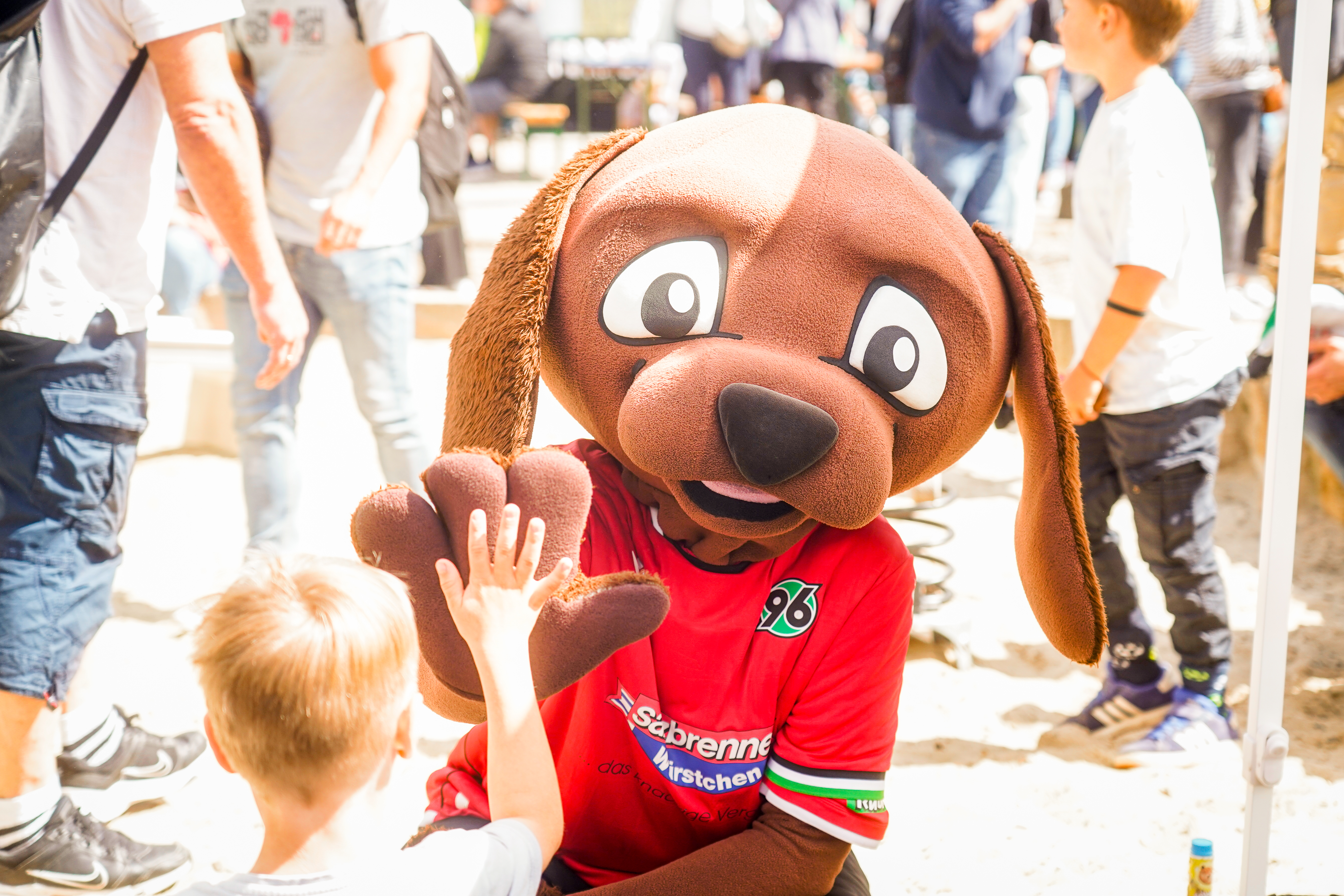 Ein Maskottchen schlägt mit einem Kind ein.